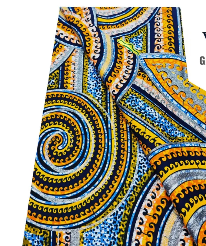 Close-up of an African wax print fabric featuring intricate blue, yellow, and black swirling patterns.