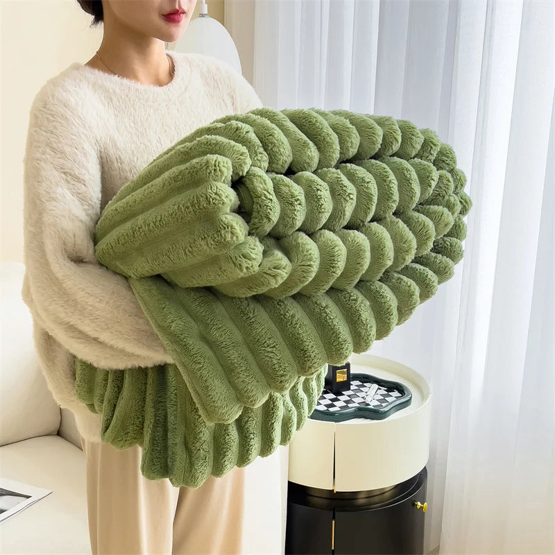 A hand holds a large, textured, olive green plush winter blanket against a white background.
