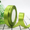 A roll of bright lime green satin ribbon with a gold edge, shown diagonally on a white and black checkered surface.