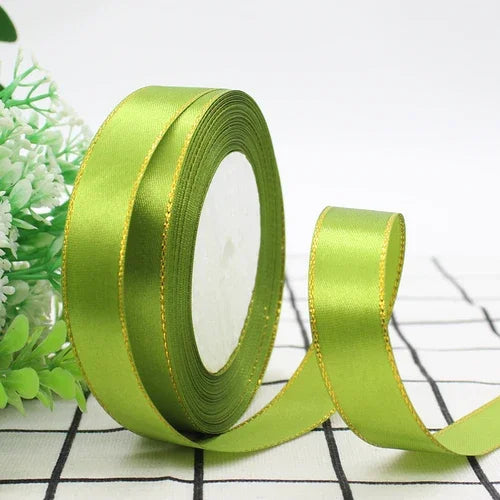 A roll of bright lime green satin ribbon with a gold edge, shown diagonally on a white and black checkered surface.