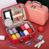 A pink portable sewing kit box open showing various sewing tools like needles, scissors, and thread storage.