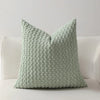 A light sage green textured decorative pillow with a ruffled edge and zipper closure.