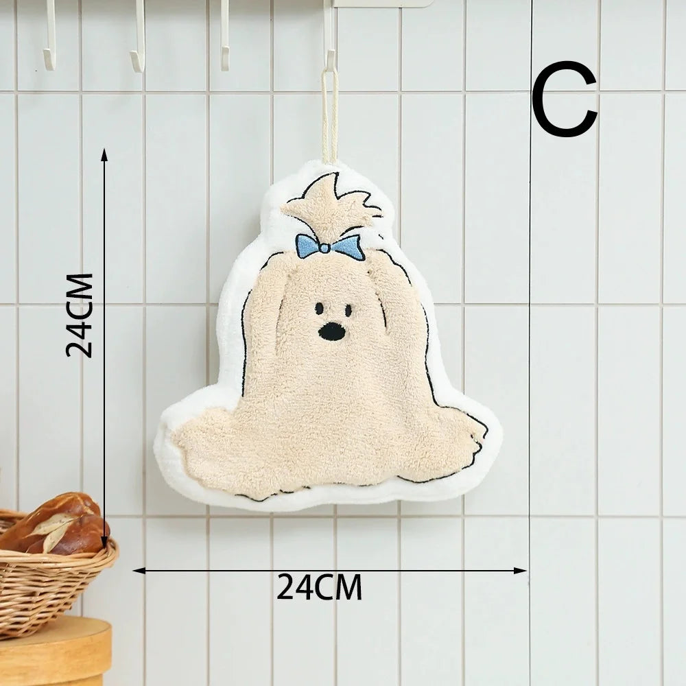A cute cartoon dog shaped hanging hand towel with a light beige body and blue bow, displayed against a white tiled background