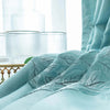 Light blue patterned curtains draped in a bright room with glass accents.