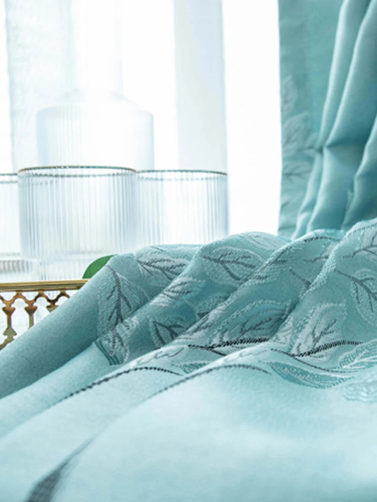 Light blue patterned curtains draped in a bright room with glass accents.