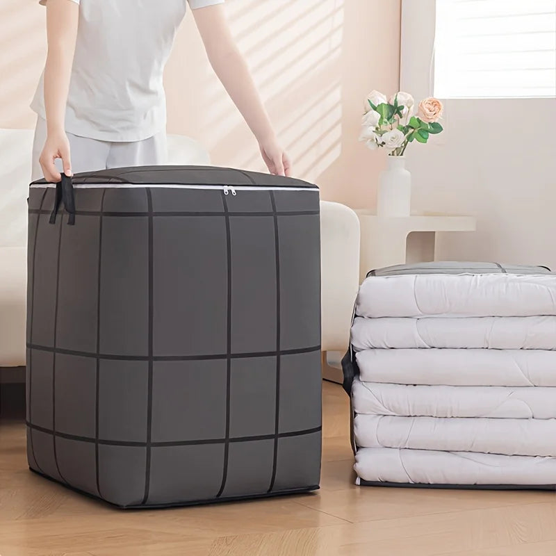 A large gray fabric storage bag with a zipper is shown next to a stack of white folded items.