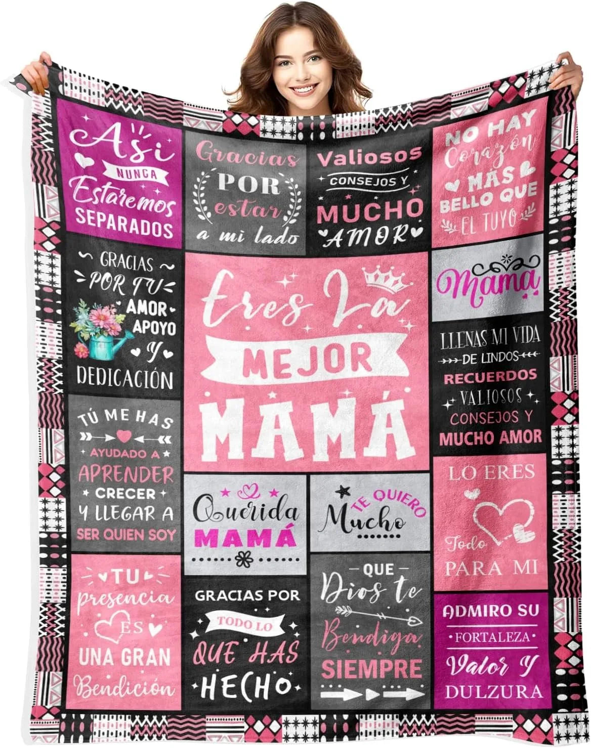 A woman holds up a pink and black patterned flannel throw blanket with Spanish text celebrating mothers.