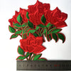 A cluster of vibrant red embroidered rose flower patches on green leaves.
