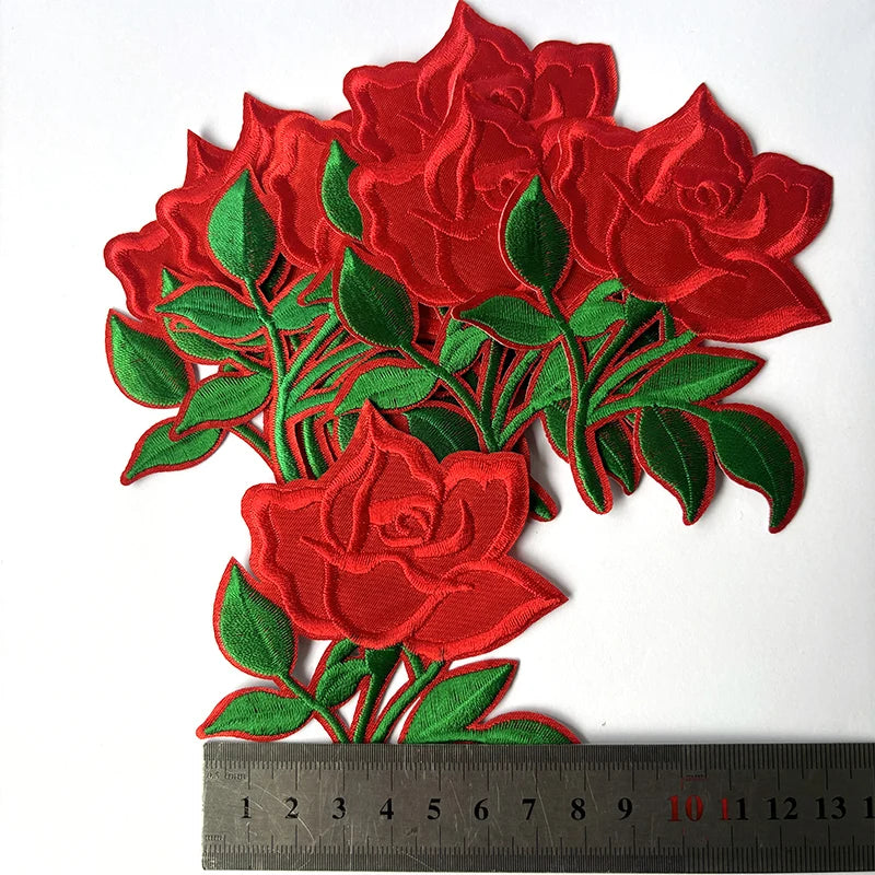 A cluster of vibrant red embroidered rose flower patches on green leaves.