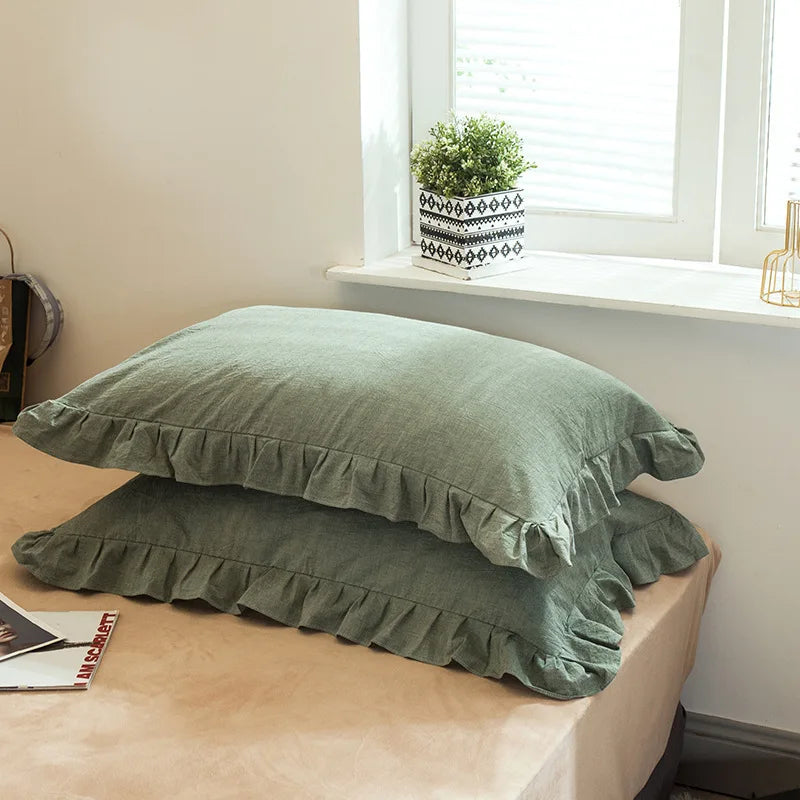 A set of two soft plaid washed cotton pillowcases with ruffled edges resting on a light-colored surface.