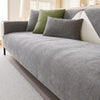 A gray chenille sofa cushion cover with olive green accent pillows on a light-colored sofa.