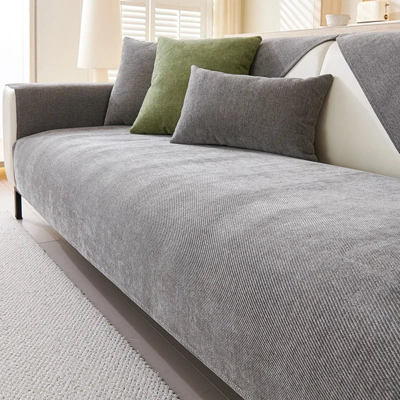 A gray chenille sofa cushion cover with olive green accent pillows on a light-colored sofa.