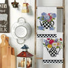 A set of two black and white checkered kitchen towels featuring a floral teapot design hanging on a wooden rack.