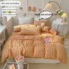 A bed dressed in a soft terracotta duvet cover set, including a duvet cover and two pillowcases, displayed in a bright room.