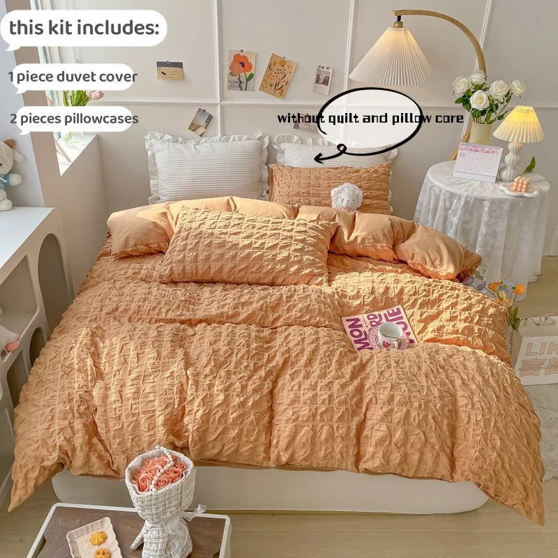 A bed dressed in a soft terracotta duvet cover set, including a duvet cover and two pillowcases, displayed in a bright room.
