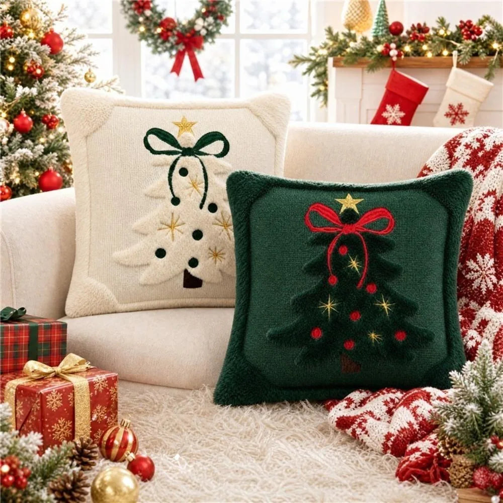 A collection of embroidered Christmas tree velvet pillow covers and festive holiday decorations on a white sofa.
