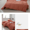 A terracotta colored minimalist duvet cover displayed on a bed with natural light and white curtains.