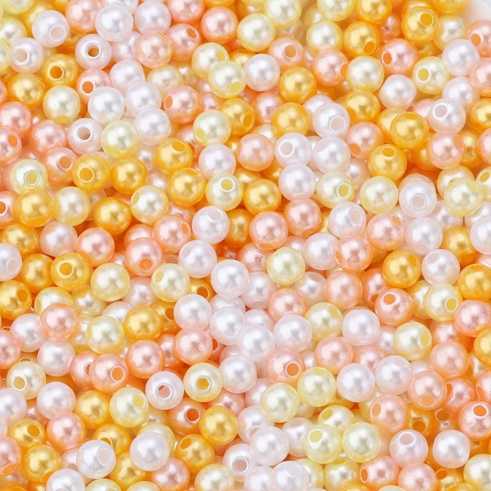 A close-up of small imitation pearl beads in shades of pink, peach, and yellow.