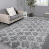A fluffy gray geometric plush area rug placed in a modern living room setting.