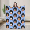 A blue throw blanket featuring a repeating pattern of anime-style characters with black hair and glasses.