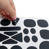 A hand is applying a black self-adhesive fabric repair patch onto a white surface with various shapes of patches visible.