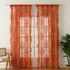 A set of sheer orange floral lace curtains hanging in a window frame.