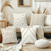A collection of cream and beige decorative pillows arranged on a sofa with natural light and dried grasses.