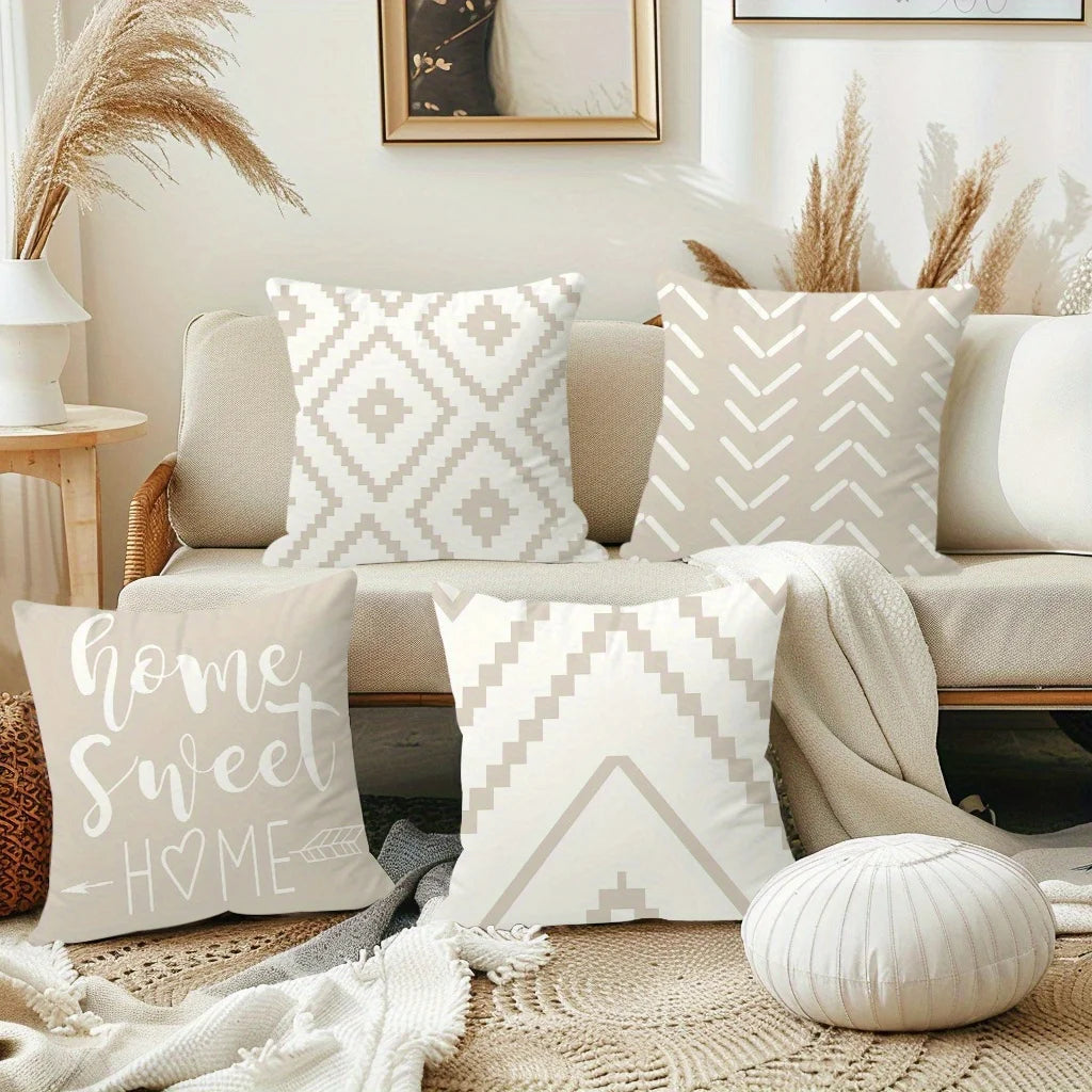 A collection of cream and beige decorative pillows arranged on a sofa with natural light and dried grasses.
