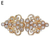 Vintage gold-toned clip brooch featuring intricate swirls and clear rhinestones