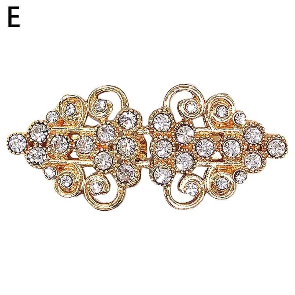 Vintage gold-toned clip brooch featuring intricate swirls and clear rhinestones