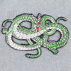 Green and white embroidered patch of a snake on denim fabric