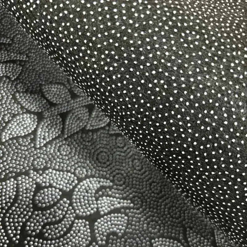 Close-up texture of a dark gray plush rug featuring a pattern of white dots and embossed lotus designs.