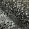 Close-up texture of a dark gray plush rug featuring a pattern of white dots and embossed lotus designs.