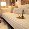A white plush sofa seat cushion cover with vertical pleats and a gold utensil resting on the surface.