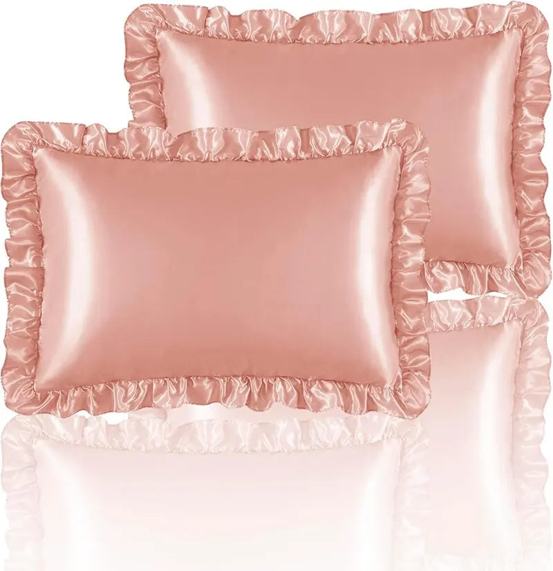 A set of two ruffled satin pillowcases in a dusty rose color with silky envelope closures.