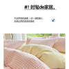 A close-up of a pink and white checkered duvet cover set with a yellow pillow on a bed.