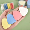 A hand holds various colored erasable fabric chalk markers for sewing, including yellow, blue, pink, and white.
