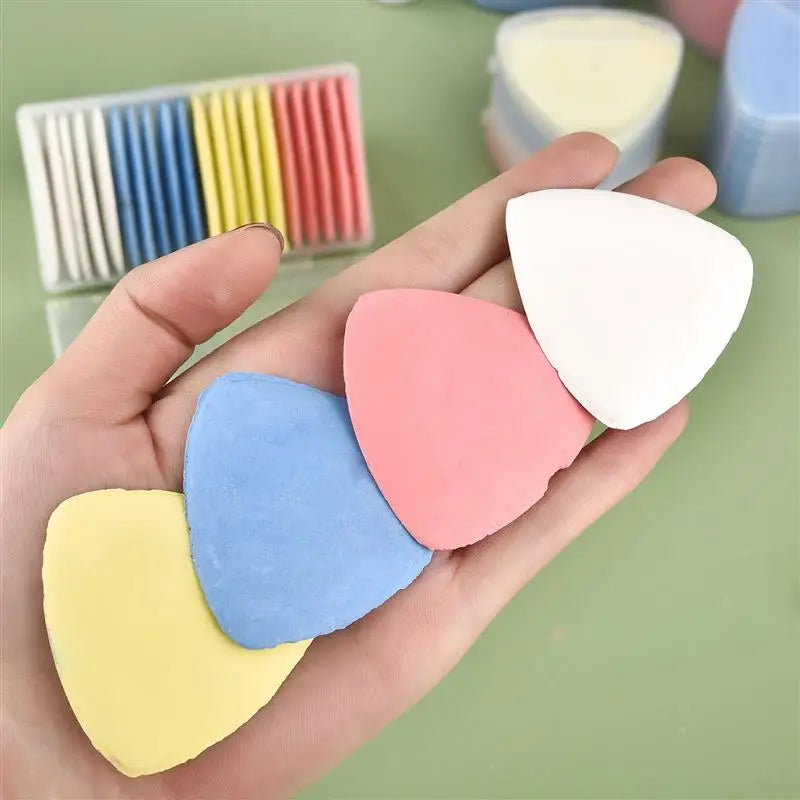 A hand holds various colored erasable fabric chalk markers for sewing, including yellow, blue, pink, and white.