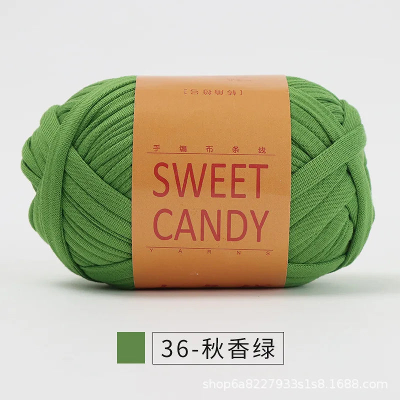 A ball of olive green hand-dyed fabric strip yarn labeled Sweet Candy with Chinese characters.