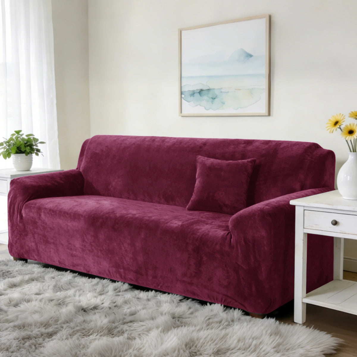 A deep burgundy stretch velvet sofa slipcover resting on a gray fluffy rug in a bright room.