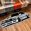 A black and white patterned car carpet is displayed in front of storage boxes labeled OasisRug.