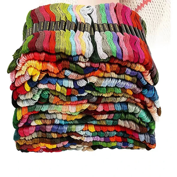 A bulk mix of multi-colored embroidery floss in various shades of red, green, blue, and yellow stacked together.
