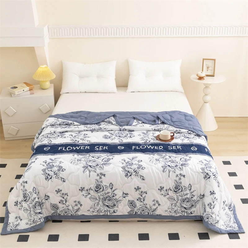 A white duvet cover with a blue floral pattern is displayed on a bed in a bright room.