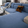 A light blue stretchy polar fleece sofa cover with a textured weave and an orange throw pillow on a modern sofa.