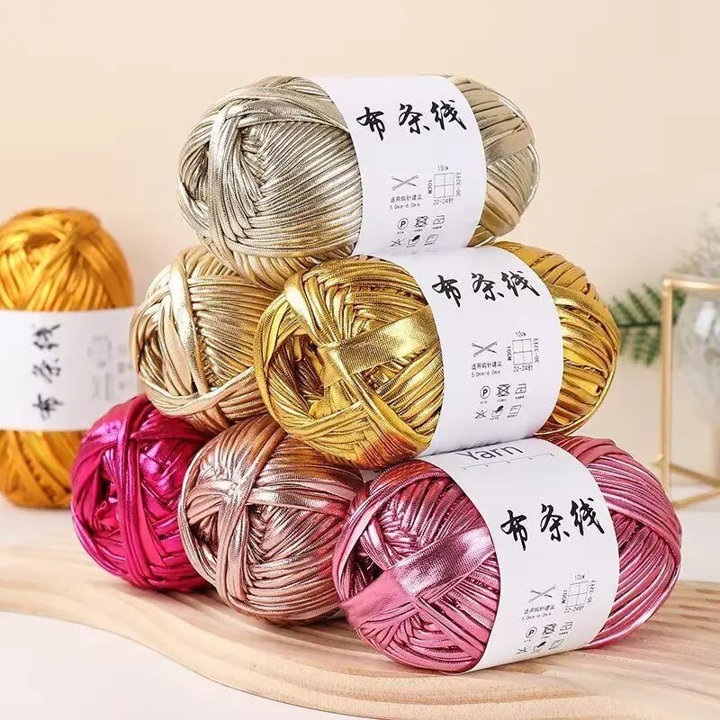 Spools of metallic fabric strip yarn in gold, pink, and silver for crochet and DIY crafts