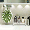 A leaf-shaped absorbent microfiber towel is displayed on a silver rack under a lighted shelf.