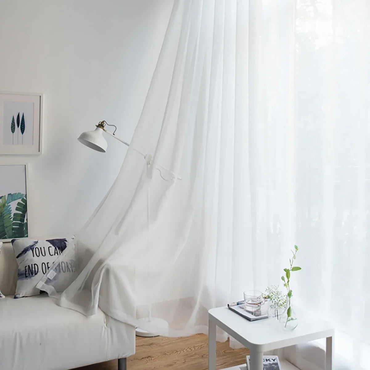 A modern sheer white curtain hangs in a window, providing soft light in a living room or bedroom setting.