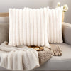 Two white plush decorative pillowcases with vertical stripes resting on a light gray sofa.