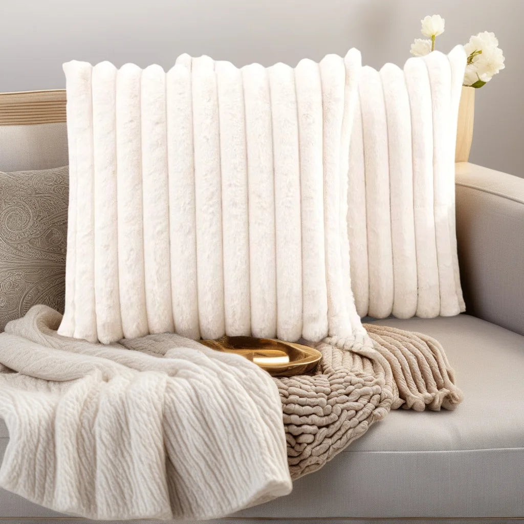 Two white plush decorative pillowcases with vertical stripes resting on a light gray sofa.