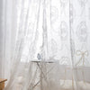 Sheer white floral lace curtains draped in a soft, romantic style